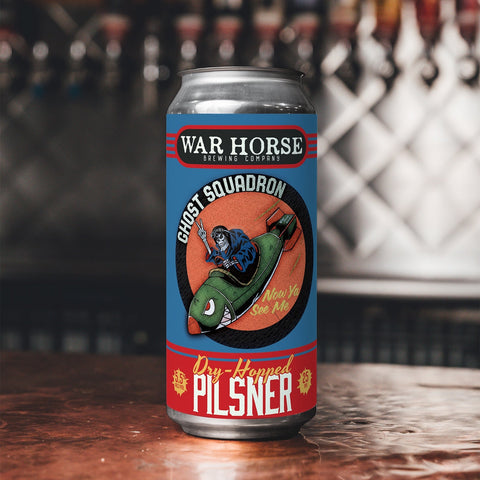War Horse Ghost Squadron Dry-Hopped Pilsner can on a bar counter with blurred bottles in the background