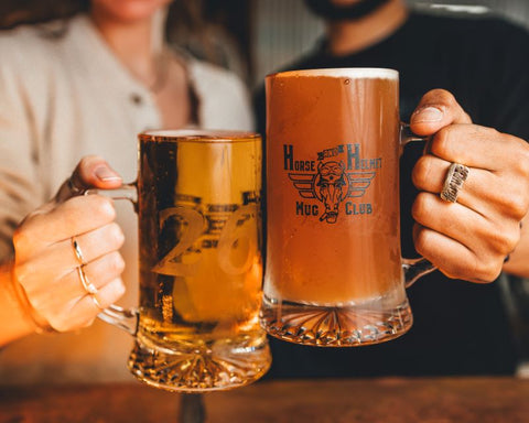 Two hands holding War Horse Brewing mug club pints